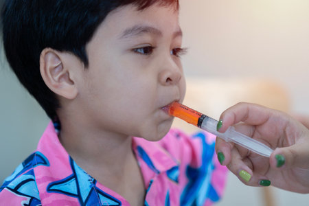Baby Asian child take an oral medical suspension an ibuprofen by syringe for relieving reduce pain fever and inflammation. medical care concept.の写真素材