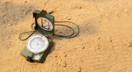 Closeup of open compass lying on yellow sand background with copy space. Business navigates recovery...