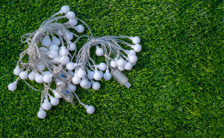 Festive electric light garland on green grass background. Party garland decoration concept. Top...