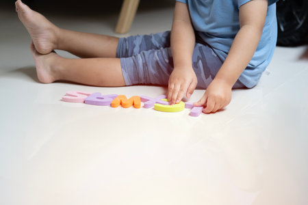 Clopped image of little toddler boy playing with colorfull alphabets collection on the floor. Educational games for kids concept.の写真素材