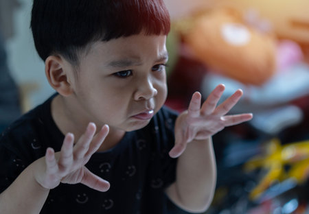 An Asian child in a black costume makes a face at the Halloween party. Kids trick or treat. Have fun...