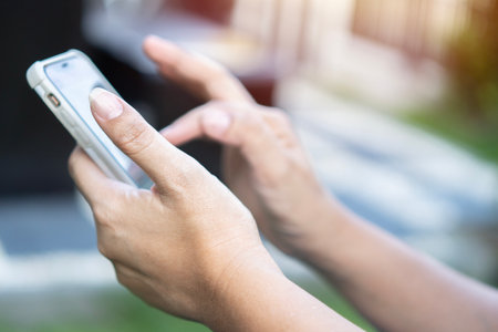 People, technology, job, occupation and age. Close up shot of senior woman hands holding smart phone. earning money via internetの写真素材
