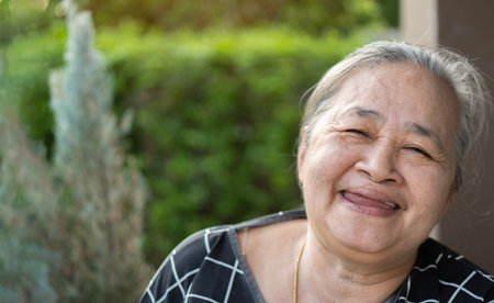 Close up portrait of kind Asian senior woman smiling at camera at home, copy space