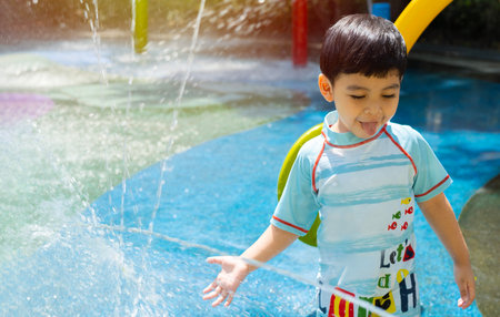 Little cute boy having fun to playing with water in park at the water playground in fountain. Summer in the city concept.の写真素材