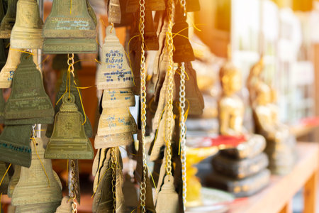 Cropped image of moving wind chimes in the temple in Thailand with old golden Buddha statue blackground. Selective focus.の写真素材