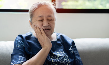 Head shot portrait senior female  touches cheek suffering from sudden tooth pain feels unhealthy and need dental service help, medical insurance conceptの写真素材