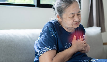 Senior Asian female suffering from bad pain in her chest heart attack at home - senior heart diseaseの写真素材