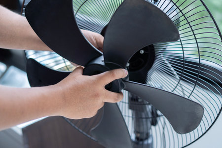 Close up horizontal photo of male hands put the parts back in place after cleaning dirty electric fan blade at home. Appliance maintenance. Household and chore concept.の写真素材