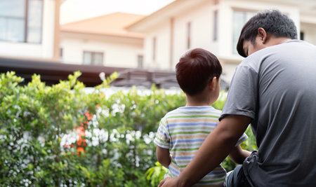 Back view of dad sit outdoor with preschooler son talking sharing thoughts or problems, loving father speak have conversation with little boy childの写真素材
