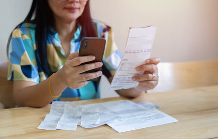 Smiling Asian woman in eyewear looking at smartphone screen, feeling satisfied with fast secure...