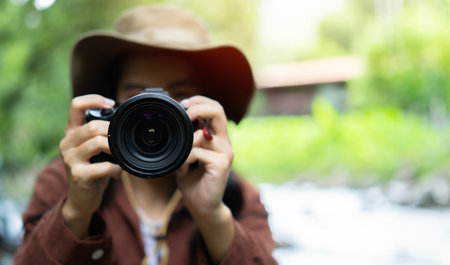 Portrait of the female photographer taking a photo with a camera in nature. Selective focus, copy space, close up.の写真素材