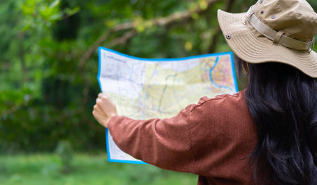 Active young woman holding a map while taking a hiking break, having fun and relaxing while spending autumn day outdoorsの写真素材