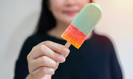 Close up shot of ice cream in hand of happy Asian woman on a sunny day. Summer time concept.の写真素材