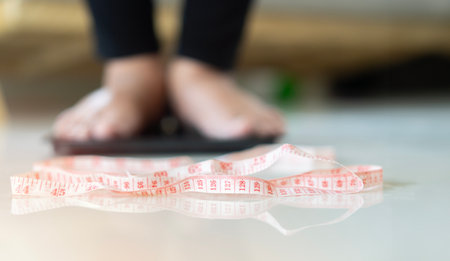 Cropped image of An elderly man is measuring her body weight while standing on a weighing machine. Selective focus at tap.の写真素材