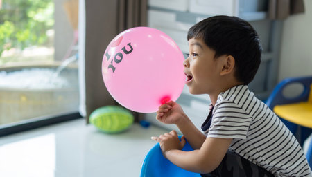 Side view of happy little Asian kids playing with colorful balloons on playtime at home. Kids activity concept.の写真素材