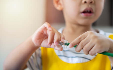 Close up hands of Asian children preschool sharpening a green color pencil. Education concept. Selective focus on hand, copy space.の写真素材