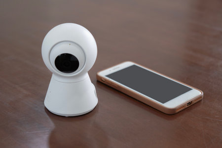 IP Camera. CCTV wireless IP security camera with 360 degrees rotating head with a smartphone on the table, Concept of home security systemの写真素材