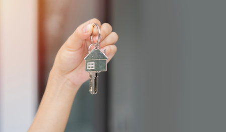 Moving house, relocation. Woman hold key house keychain in new apartment. Move in new home.の写真素材