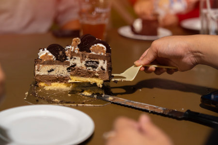 Birthday cake, excited and family at party to celebrate and cut slice together for dessert. Celebration or holiday concept. Selective focus on hand.の写真素材