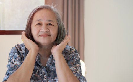 Elderly beautiful Asian woman with a short haircut in a blue striped shirt and sit on a chiar at...
