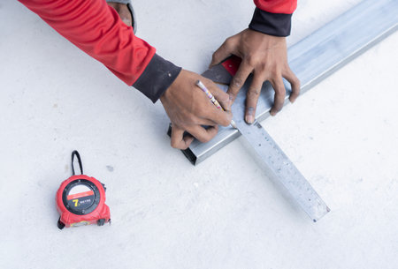 Measuring with a square and measuring tape. Tool for measuring in technician hands on workshop outdoor. Close-up, selective focus.の写真素材