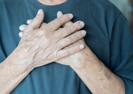 Crop close up of old man hold hands in prayer at heart chest feel religious superstitious. Adult...
