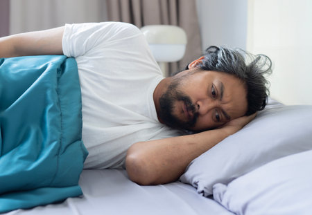 Sleeping disorder. Closeup of exhausted grey-haired middle aged man lying in bed in the morning,...