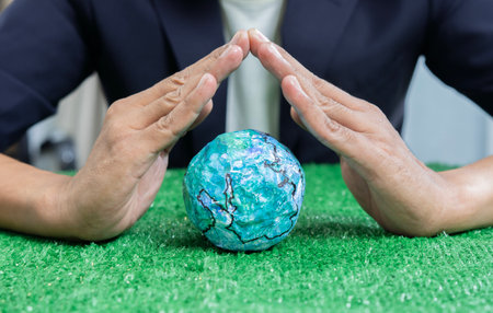 Hands of business man over the earth model on a green table to protect nature. Save and care World...