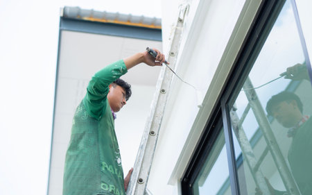 House painting and renovation business concept. 

Asian male painting wall outstide house from the ladder. Construction concept.の写真素材