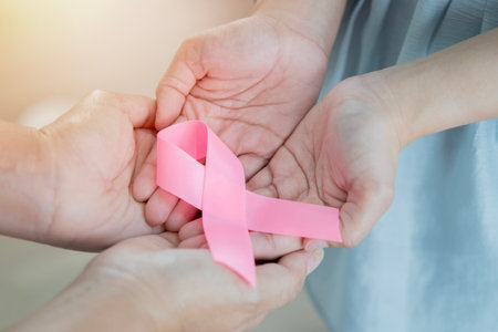 Selective focus of adult and young hands holding pink ribbons, Breast cancer awareness, abdominal cancer awareness and October Pink day background, world cancer dayの写真素材