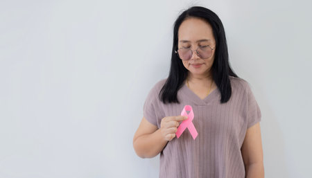 Portrait picture of happy Asian woman with pink ribbon, great for prevention breast cancer concept. Copy space.の写真素材