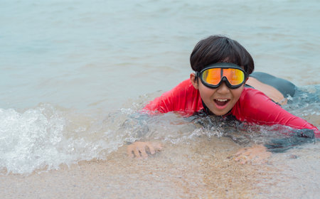 Happy child playing in the sea. Kid having fun outdoors. Summer vacation and healthy lifestyle concept. Copy space.の写真素材