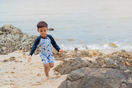 Cute Asian child boy wearing a swimming suit and having fun on sandy beach in summer. Copy space.の写真素材