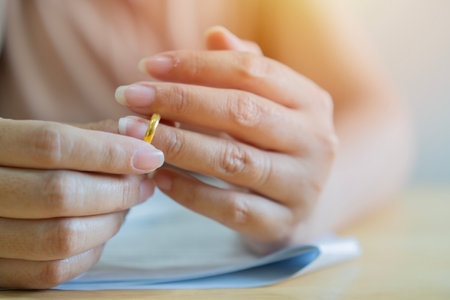 Divorce concept. Woman taking off wedding ring and ready to sign divorce papers. Close up, selective focus.の写真素材