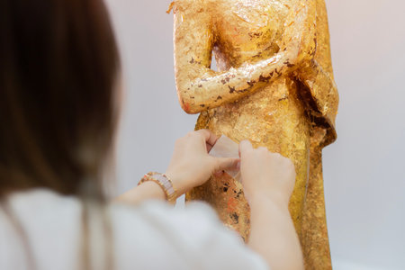 A woman respects the Buddha statue by putting the gold foil. The body same culture for making merit. Traveling to Thailand and Temple concept.の写真素材