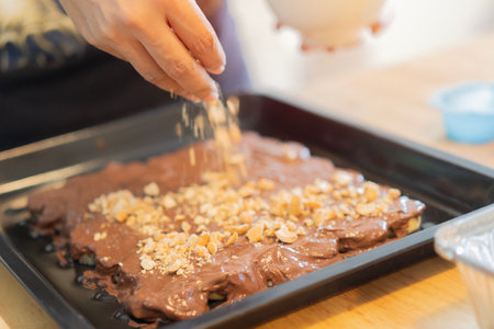 Chef, baking and banana cake with penuts and chocolate in a kitchen by woman preparing a sweet desert or a birthday. Selective focus.の写真素材