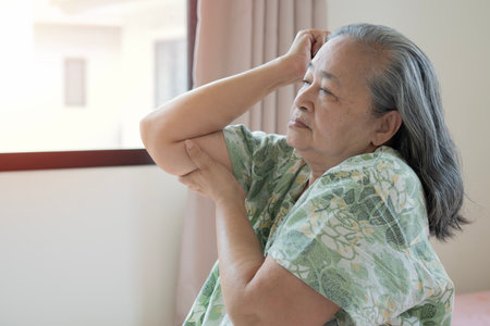 Old Asian woman touching wrist feeling hurt joint pain having osteoarthritis disease. Health problemの写真素材