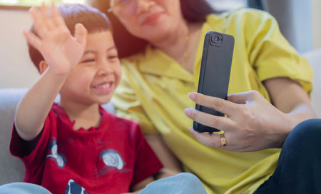 Asian mother and her son have video call conference with family having fun together. Selective focus.の写真素材