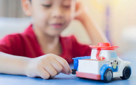 Cute little Asian boy child kids, preschooler playing with truck, car toy at home. Selective focus.