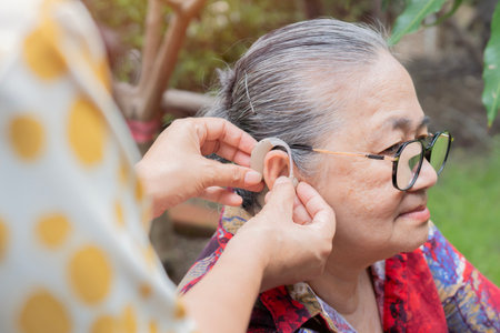 Old woman and daughter hands with hearing aid, help and support with healthcare at home. Person with disability concept.の写真素材