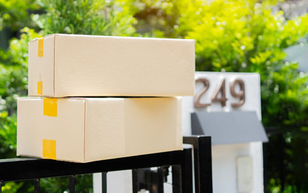 Stack of parcels delivered near front gates, two carton boxes delivered by courier and left oudside near gate. Focus on parcel.の写真素材