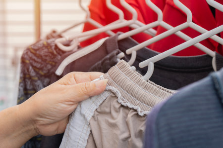 Selective focus of a housewife hand doing laundry, washing and hanging shirts on clothesline at...