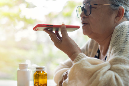 Side view of senior woman at home, communicating with the doctor via mobile phone before take a medicine. Health and Medical conceptの写真素材