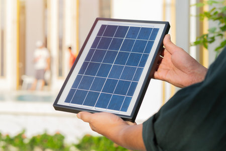 Young man hands standing in the public park and holding photovoltaic mini solar panel. Concept of renewable energy, technology.の写真素材