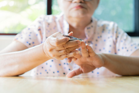 Side view shot of elderly Asian woman sitting and cutting her finger nails at home. Selective focus.の写真素材