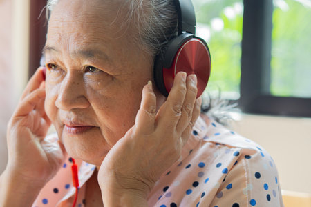 Some tunes will stay my favourite forever. Shot of a senior woman wearing headphones while listening to music at home.の写真素材