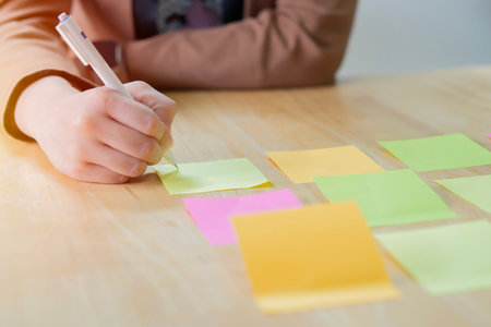 Adult business Asian woman write a post it and stick on a wooden board at office. Brainstorming...