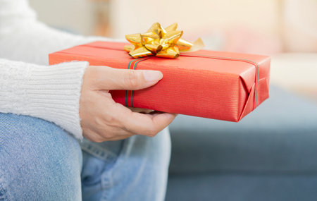 Close-up image of senior woman sitting on sofa and holding Christmas present. Celebrate present concept.の写真素材