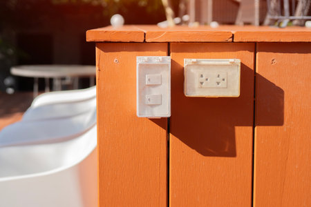 Outdoor white electrical outlet with cover on bright brown wooden wall. Selctive focus.