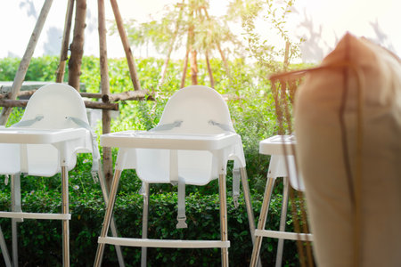 The white baby high chairs prepared for service in a garden atmosphere restaurant. Selective focus.の写真素材